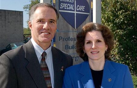 Two professionally dressed individuals stand in front of a sign that reads "Griswold Special Care," showcasing their local home care services.