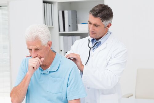 A doctor uses a stethoscope to listen to an older man's back
